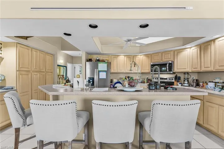 Kitchen featuring a raised ceiling, light tile patterned floors, stainless steel appliances, a kitchen island, and a kitchen breakfast bar