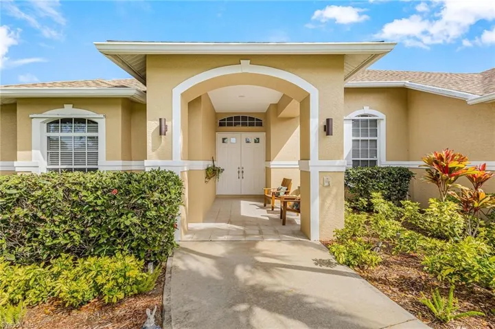 Property entrance with roof with shingles and stucco siding