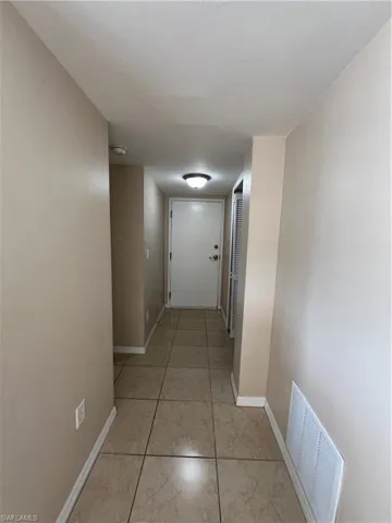 Corridor featuring light tile patterned floors, baseboards, and visible vents