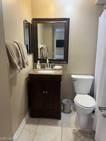 Full bathroom featuring curtained shower, vanity, and light tile patterned flooring