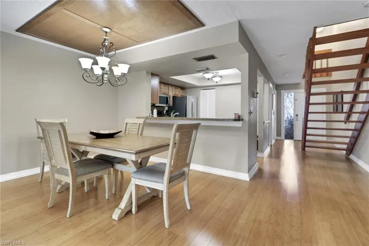 Dining room featuring light wood-style flooring, a chandelier, and stairs