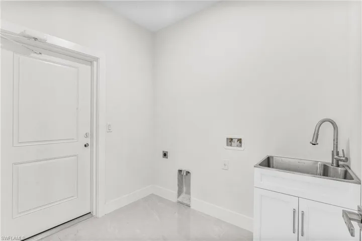 Washroom with hookup for a washing machine, sink, electric dryer hookup, and cabinets