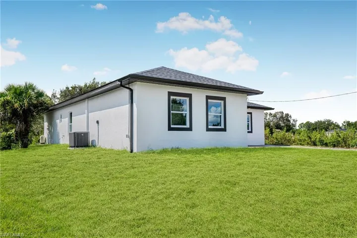 View of side of property with a lawn and central air condition unit