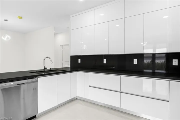 Kitchen featuring stainless steel dishwasher, white cabinetry, and sink