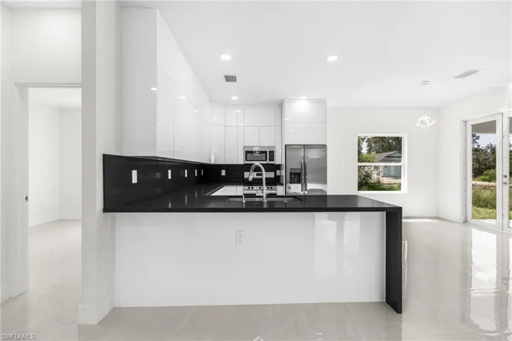 Kitchen featuring kitchen peninsula, sink, stainless steel appliances, and white cabinets