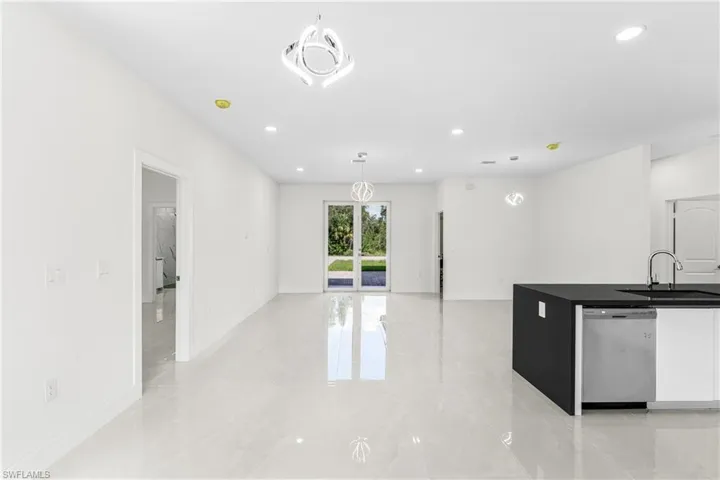 Kitchen with dishwasher, white cabinetry, decorative light fixtures, and sink
