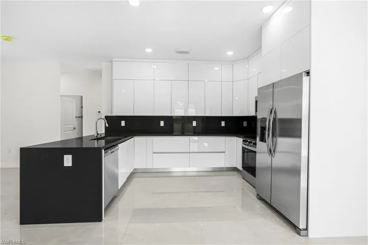 Kitchen featuring light tile patterned flooring, white cabinetry, sink, and stainless steel appliances