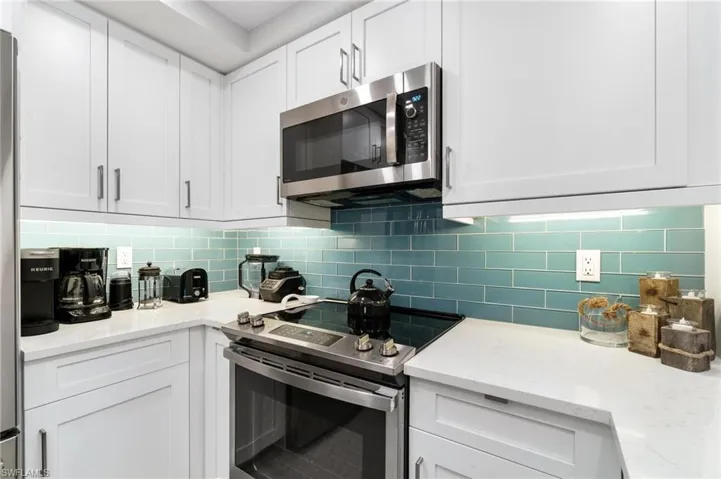 Kitchen featuring white cabinetry, stainless steel appliances, and light stone counters