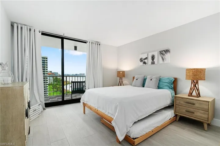 Bedroom featuring a water view, access to exterior, and a wall of windows