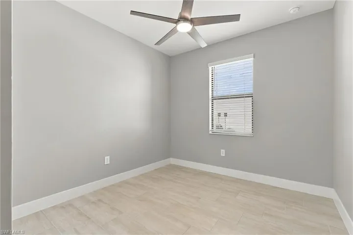 Neutral-toned walls, wood-finish tile flooring, and a central ceiling fan with integrated lighting