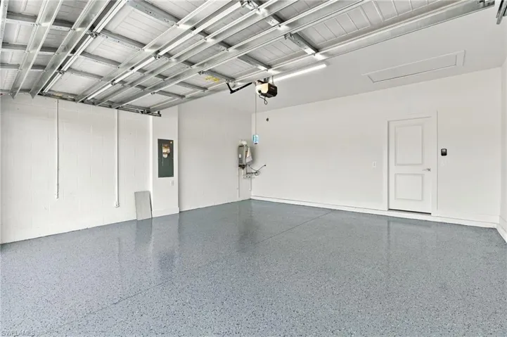 Finished garage featuring epoxy-coated flooring, painted concrete block walls, and an overhead lighting fixture
