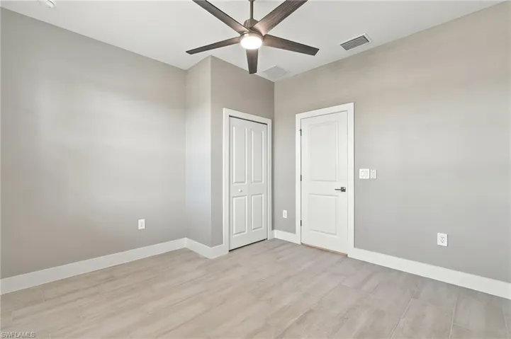Interior room featuring wood-finish tile flooring, neutral wall texturing, and a modern ceiling fan with integrated lighting
