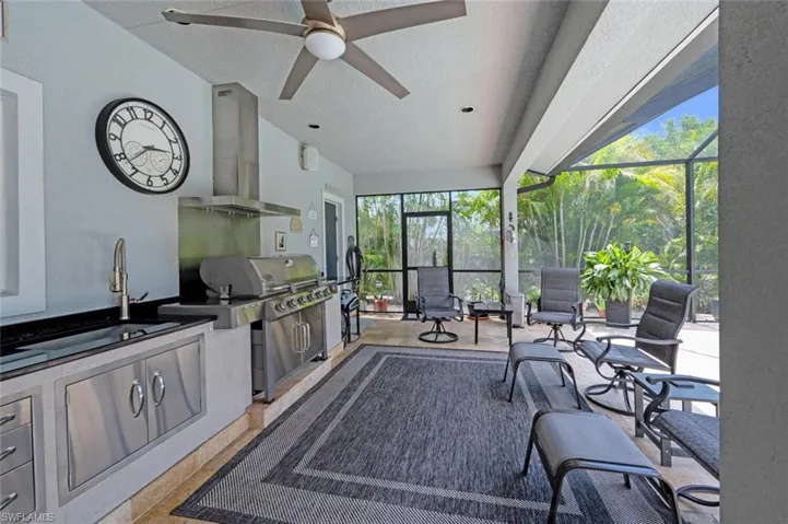 Sunroom featuring exterior kitchen, ceiling fan, and vaulted ceiling