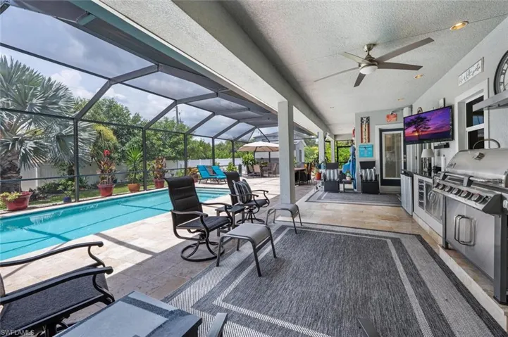 View of patio / terrace featuring exterior kitchen, an outdoor pool, a ceiling fan, and a lanai