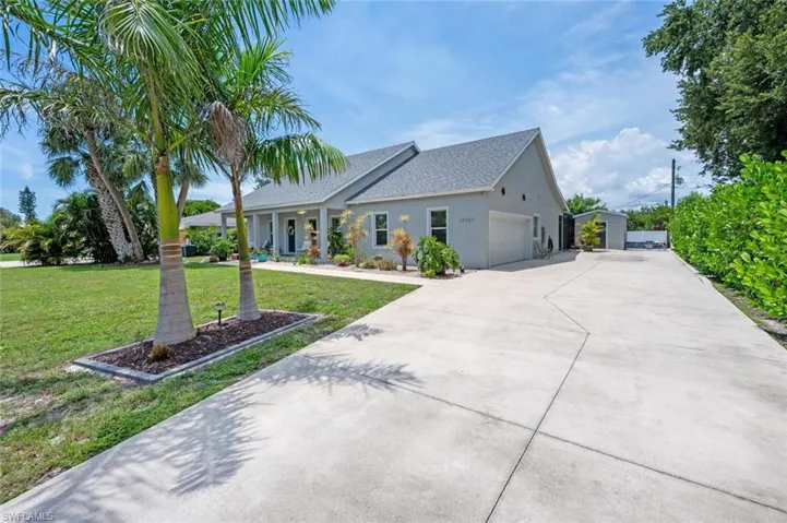 View of front of house featuring a garage, driveway, a front lawn, roof with shingles, and stucco siding