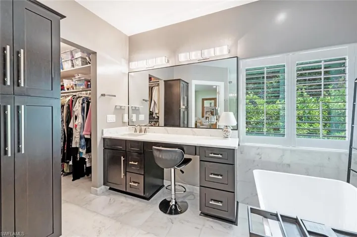 Bathroom featuring a freestanding tub, vanity, marble look tiles, and a spacious closet