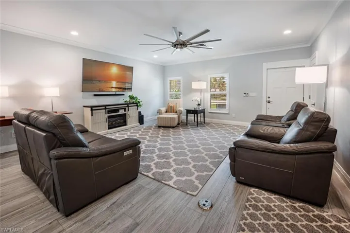 Living area featuring ceiling fan, ornamental molding, recessed lighting, wood finished floors, and a glass covered fireplace