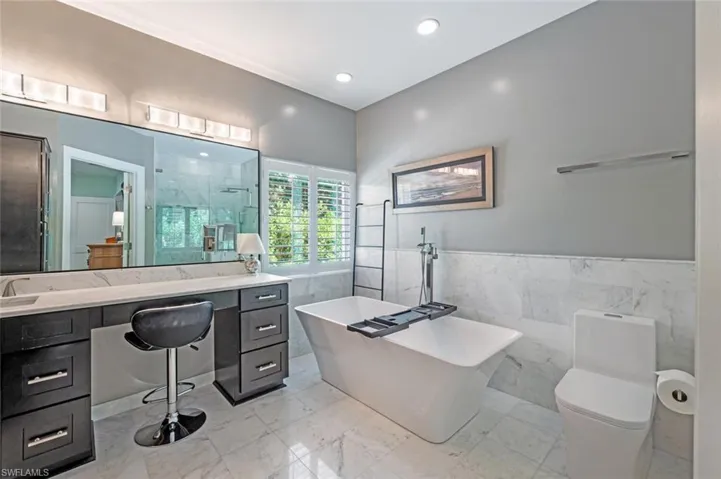 Bathroom with tile walls, vanity, a freestanding bath, a stall shower, and marble finish floors