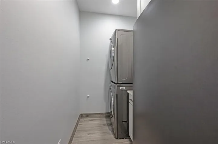 Laundry room featuring estacked washer and dryer and light wood-style flooring
