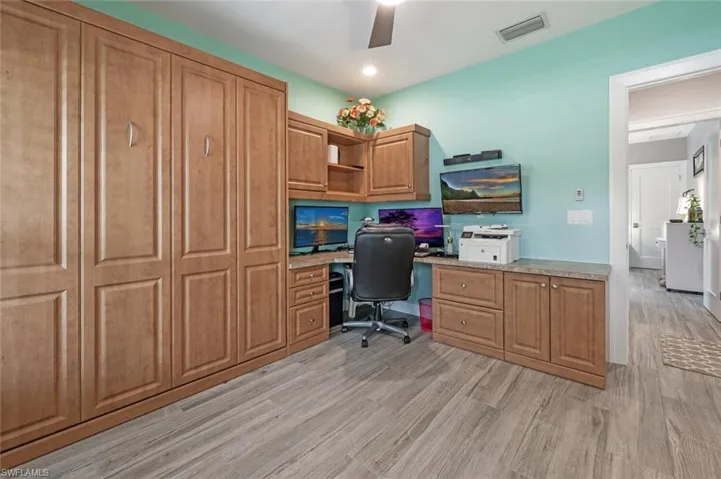 Home office with light wood-style flooring, a ceiling fan, and built in desk