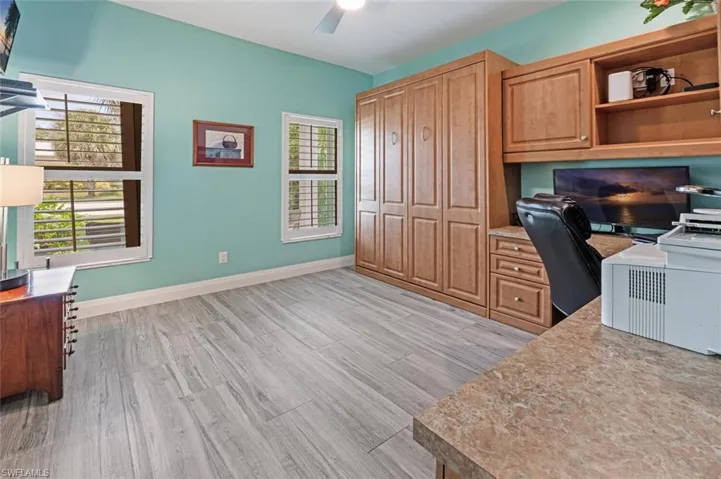 Office featuring a ceiling fan, healthy amount of natural light, light wood-style flooring, and built in desk