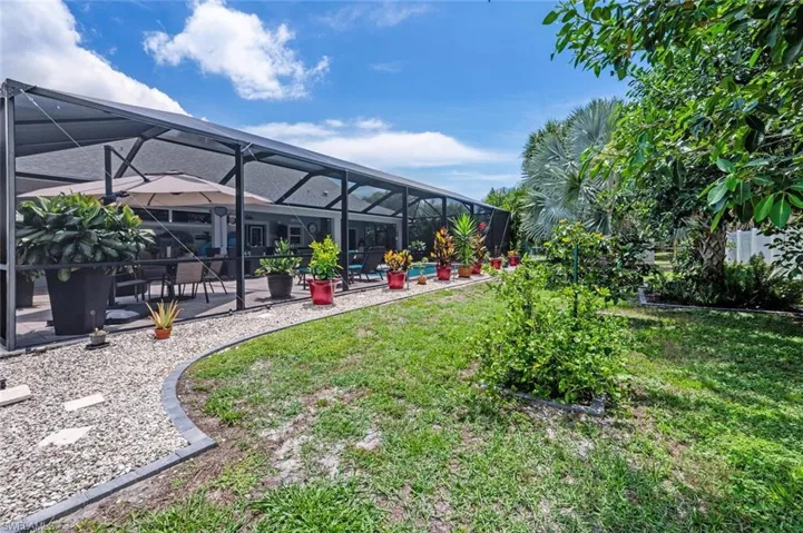 View of grassy yard with a patio, glass enclosure, and a pool