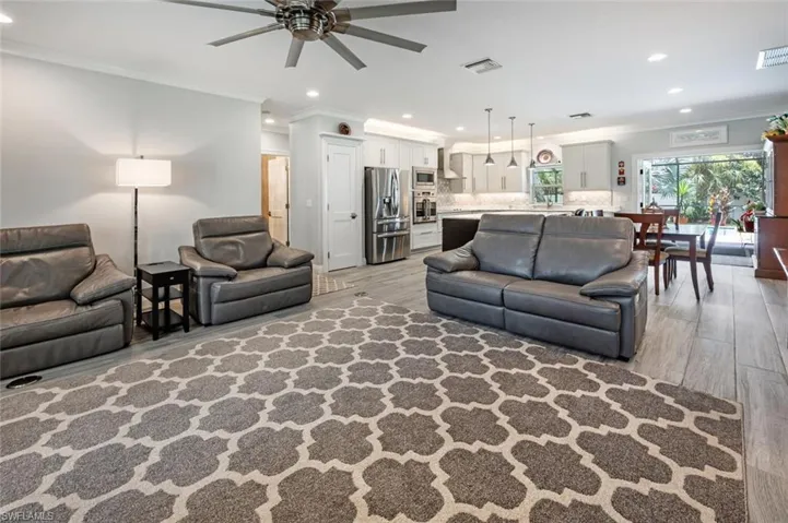 Living area with light wood-style flooring, recessed lighting, ceiling fan, and crown molding