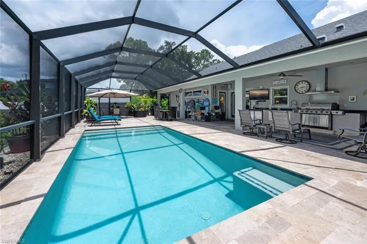 Outdoor pool with a patio area, a grill, a ceiling fan, and glass enclosure
