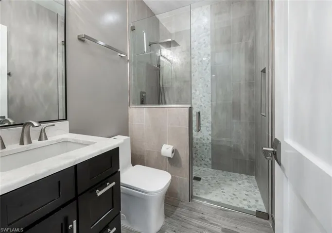 Bathroom with vanity, a stall shower, and wood finished floors
