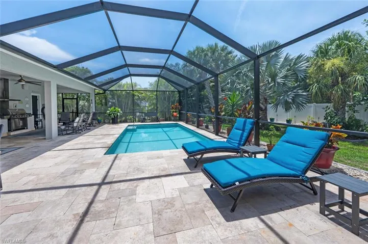 Swimming pool with area for grilling, a patio area, ceiling fan, and a lanai