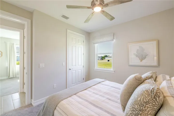 Carpeted bedroom with a ceiling fan and tile patterned flooring