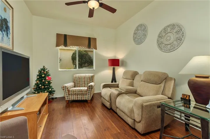 Den featuring dark Pergo / wood-style floors, ceiling fan, and vaulted ceiling