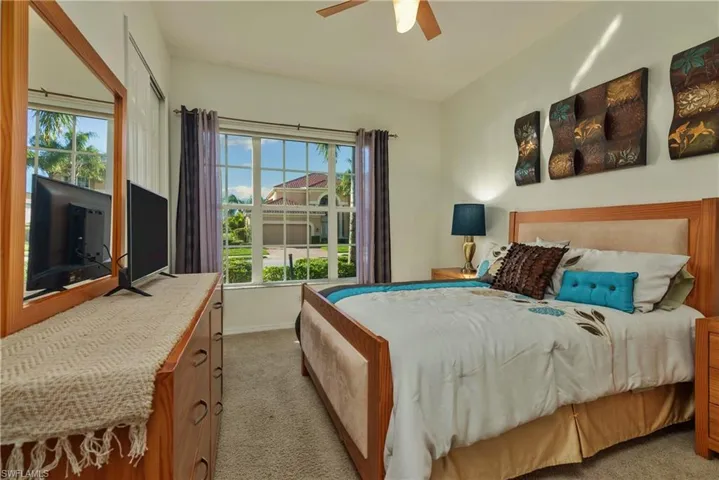 Carpeted bedroom with multiple windows and ceiling fan
