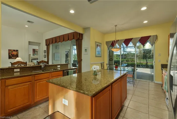 Kitchen featuring sink, decorative light fixtures, dark stone countertops, a center island, and white fridge