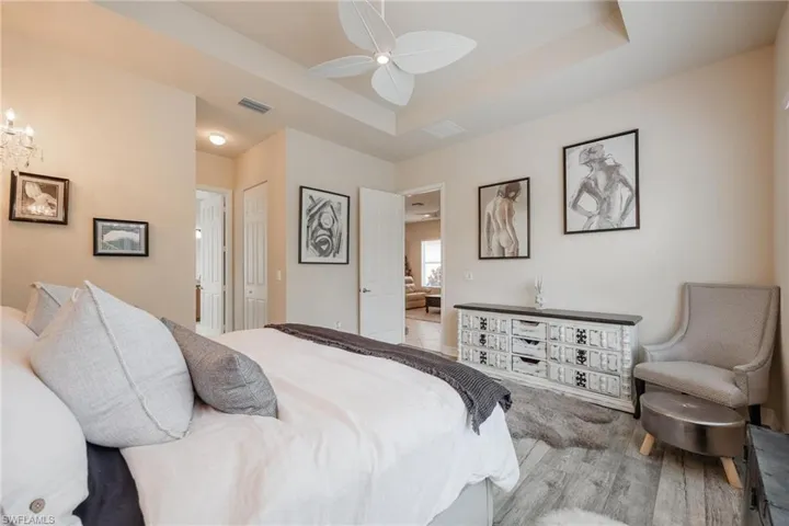 Bedroom featuring hardwood / wood-style flooring, ceiling fan, and a raised ceiling