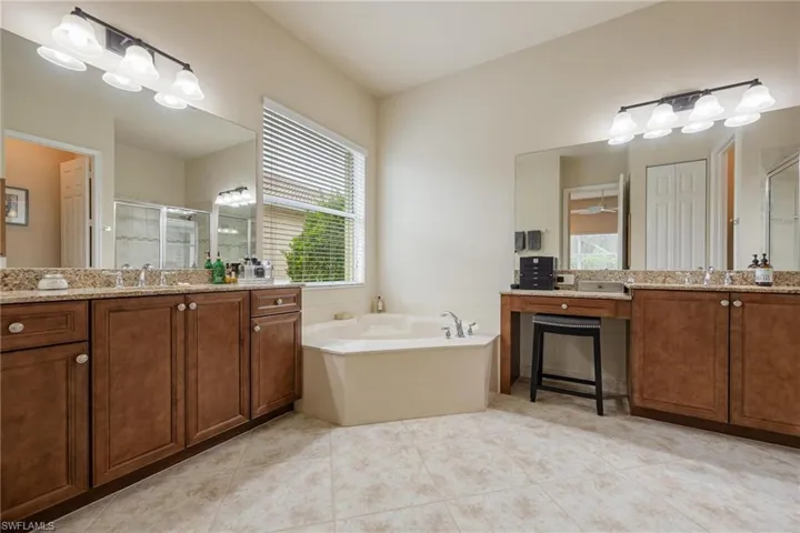 Bathroom with vanity, a bath, and tile floors