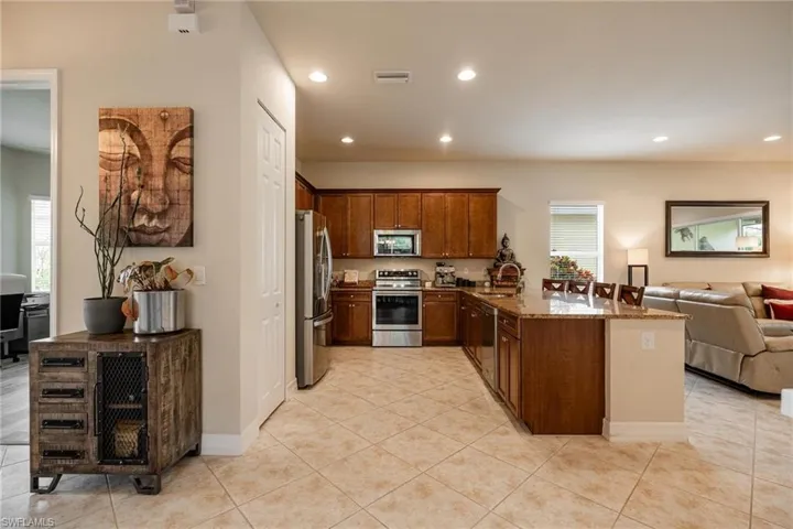 Kitchen with light stone countertops, light tile flooring, kitchen peninsula, and stainless steel appliances