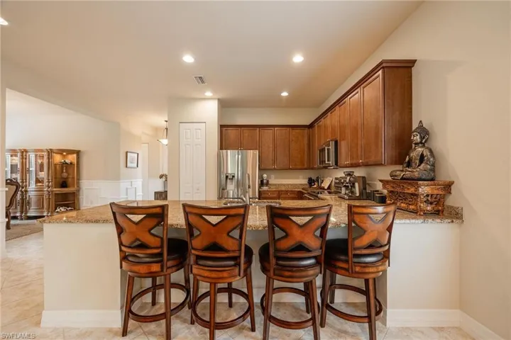 Kitchen featuring light stone countertops, kitchen peninsula, light tile floors, and appliances with stainless steel finishes