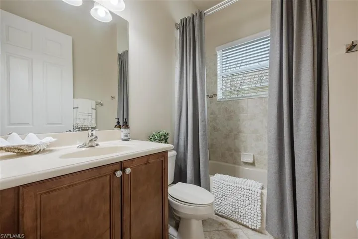 Full bathroom with tile floors, shower / bath combination with curtain, toilet, and large vanity