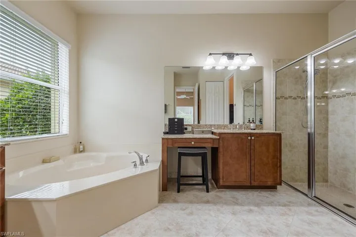 Bathroom with tile flooring, separate shower and tub, vanity, and plenty of natural light