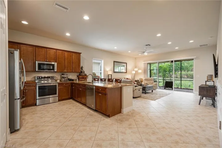 Kitchen featuring stainless steel appliances, ceiling fan, light tile flooring, and kitchen peninsula