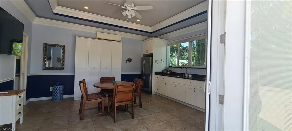 Dining space featuring a raised ceiling, ornamental molding, ceiling fan, a wall unit AC, and recessed lighting