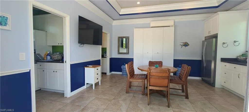 Dining room featuring a tray ceiling, crown molding, a wall mounted AC, and light tile patterned floors