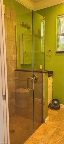 Full bath with a shower stall, tile patterned flooring, and crown molding