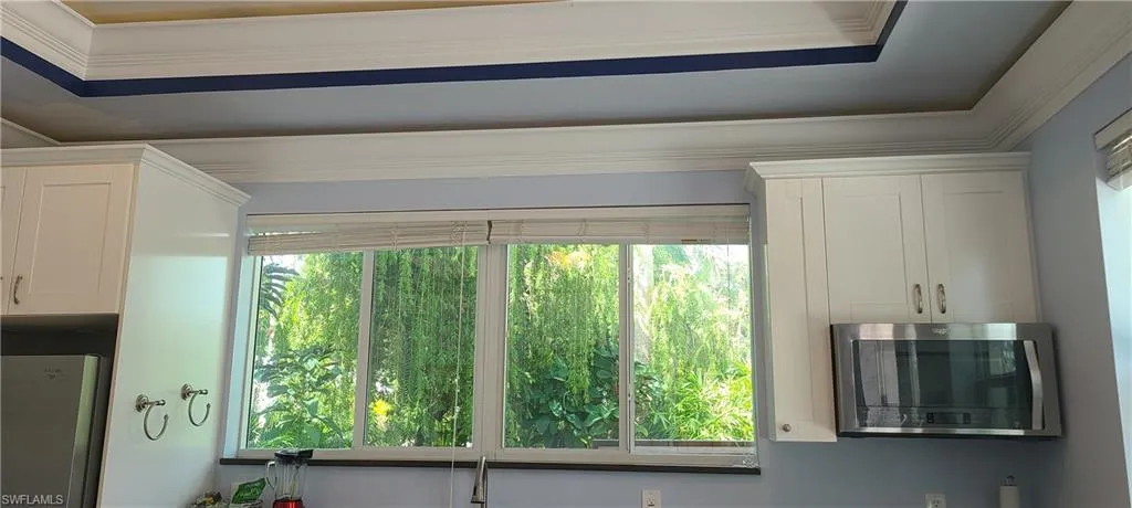 Kitchen view of stainless steel appliances, crown molding, and white cabinets