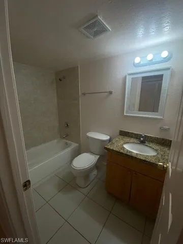 Full bathroom featuring tile patterned flooring, a textured ceiling, toilet, vanity, and shower / bathing tub combination