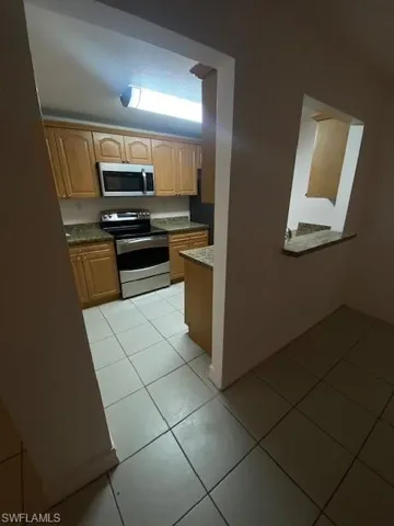 Kitchen featuring light brown cabinetry, stove, and light tile patterned floors