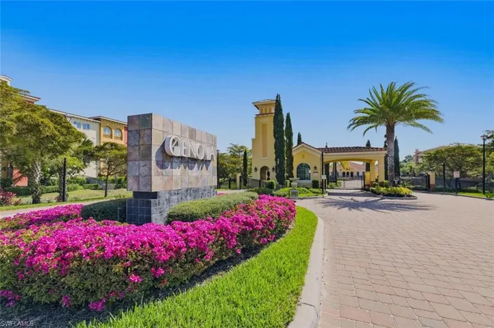 Stone-clad community signage featuring vibrant bougainvillea landscaping