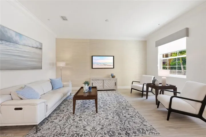 Spacious interior featuring light wood-finish flooring, crown molding, and a textured accent wall