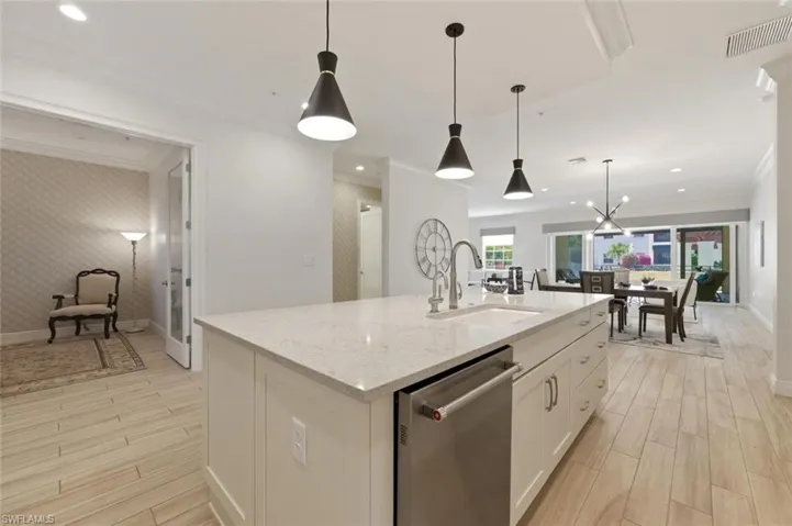 Kitchen island with a built-in stainless steel dishwasher, undermount sink, and light-toned countertop